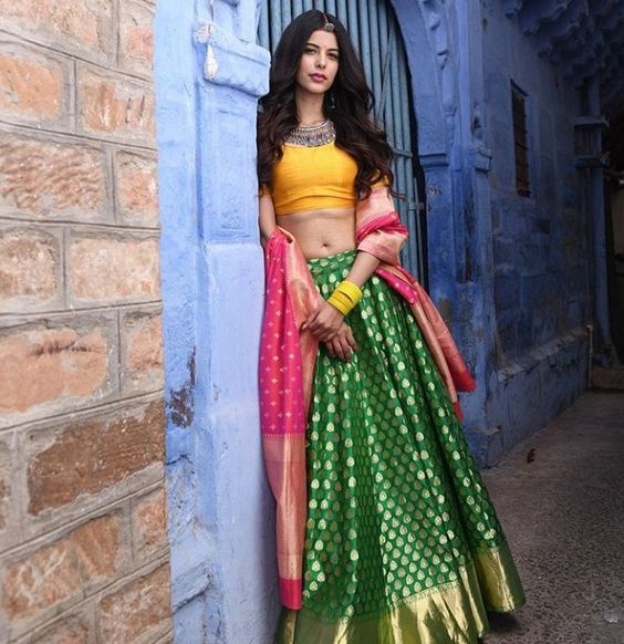 YUGA - Women's Fashion & Lifestyle - A beautiful model in Dark Green  kanjeevaram lehenga with contrast yellow blouse and carrying Rani pink  Banarasi Dupatta around the elbows looks stunning and no